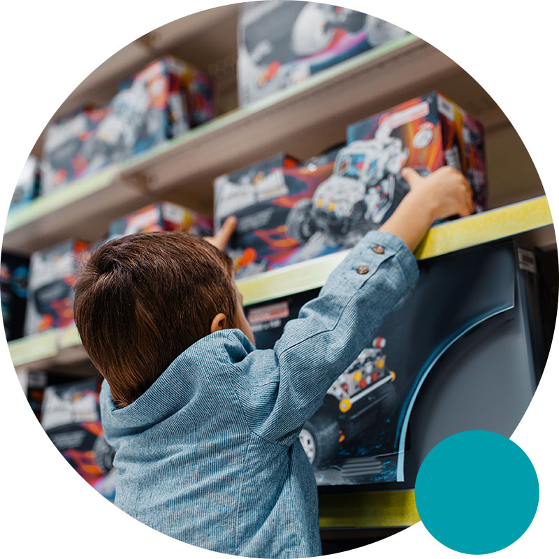 child grabbing a toy off a shelf in a toy store